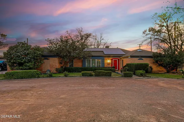 a front view of house with yard and trees in the background