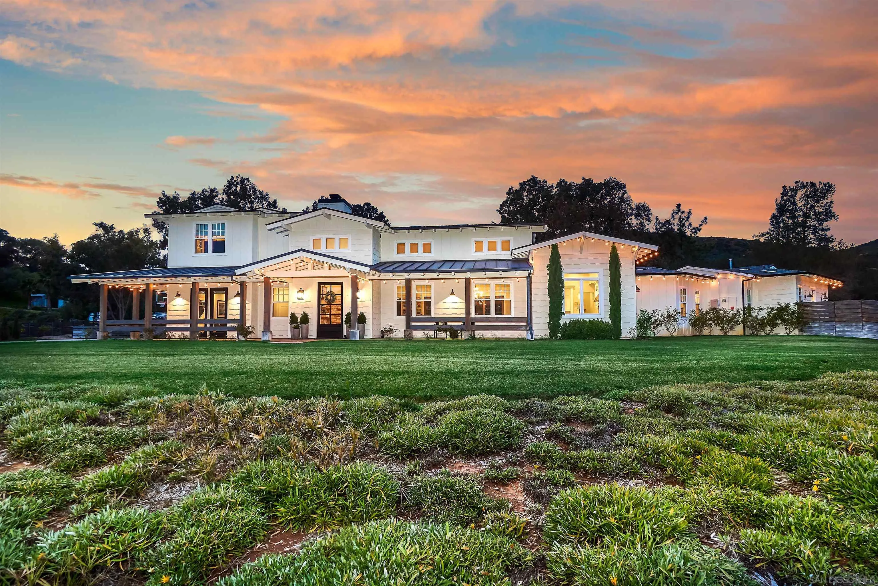 a view of a big house with a big yard and large trees