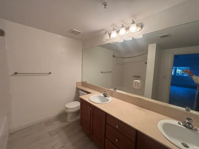 a bathroom with a double vanity sink mirror and toilet