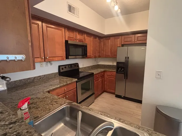 a kitchen with stainless steel appliances granite countertop a refrigerator and a stove top oven