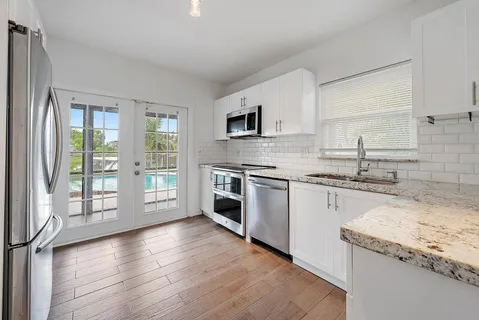 a kitchen with granite countertop stainless steel appliances a stove sink and cabinets