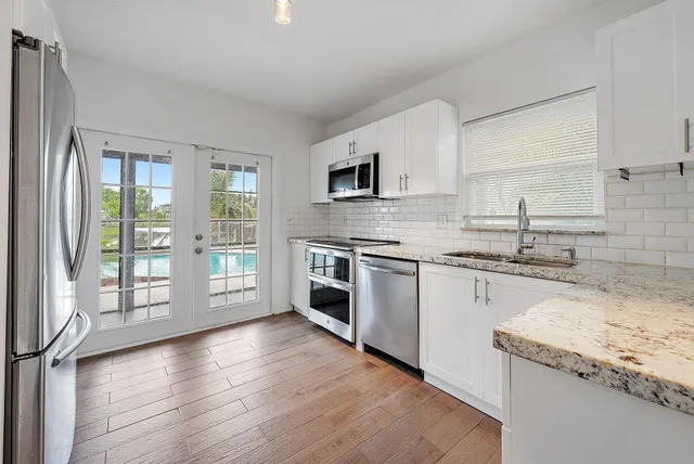 a kitchen with granite countertop stainless steel appliances a stove sink and cabinets