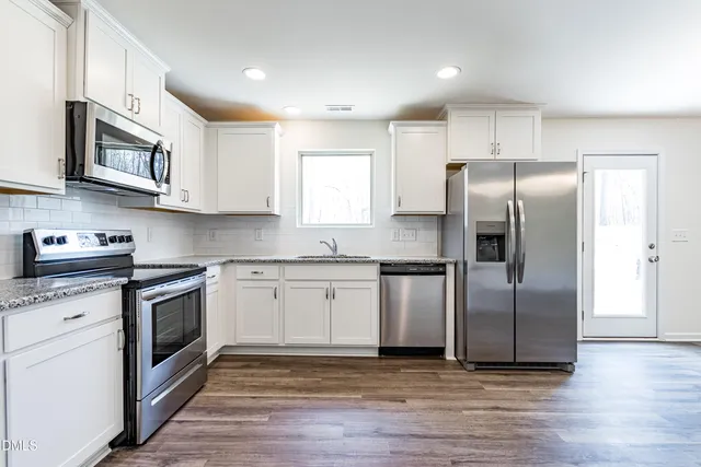 a kitchen with stainless steel appliances granite countertop a refrigerator sink and microwave