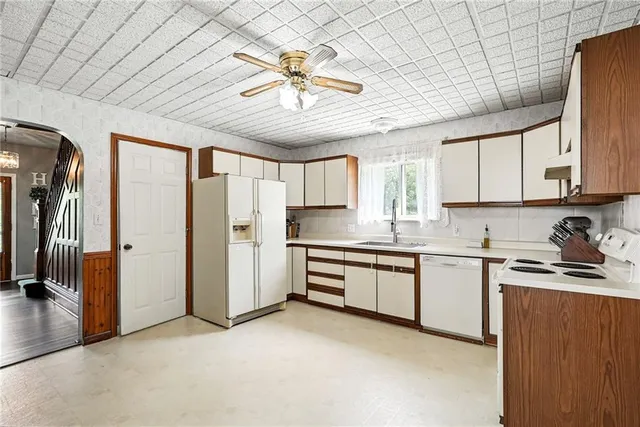 a kitchen with stainless steel appliances granite countertop a refrigerator a sink dishwasher a stove with white cabinets and wooden floor