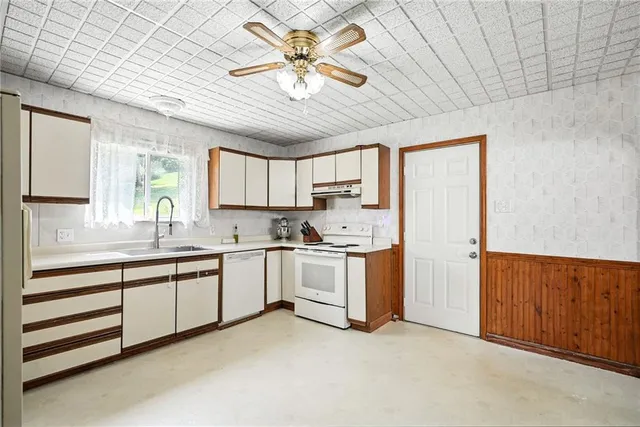 a large kitchen with stainless steel appliances granite countertop a sink a stove cabinets and entryway