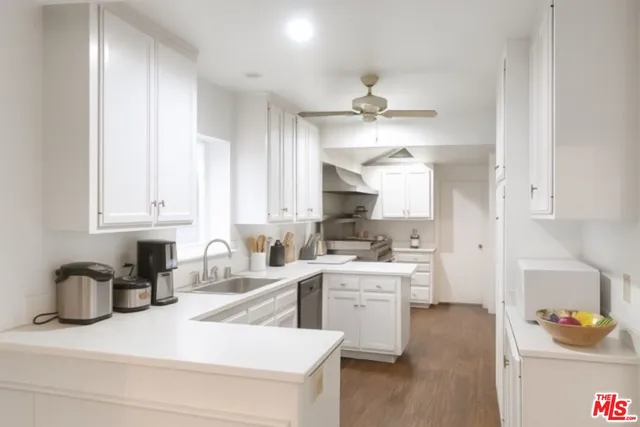 a kitchen with a sink dishwasher and white cabinets with wooden floor