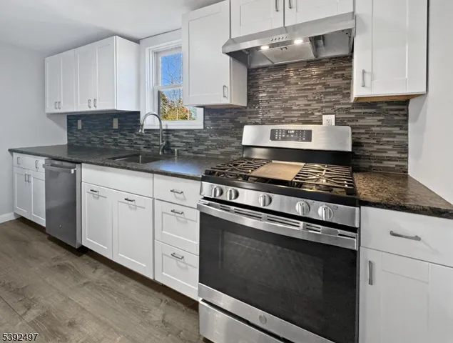 a kitchen with granite countertop white cabinets appliances and a sink