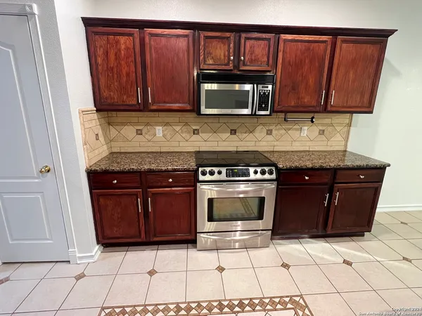 a kitchen with granite countertop a stove and a microwave
