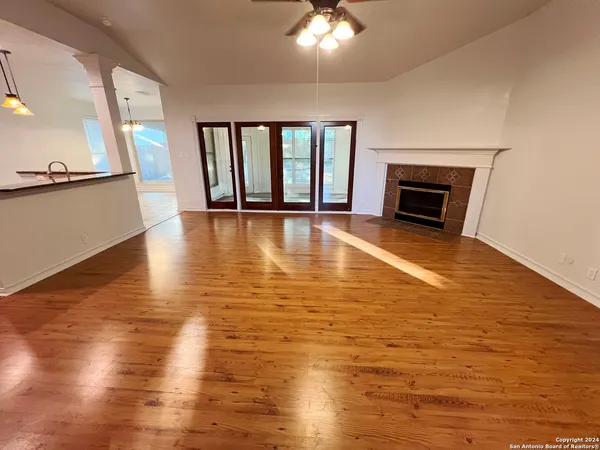 a view of an empty room with a fireplace and wooden floor
