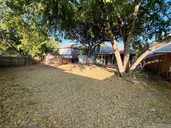 a view of a yard with wooden fence and a large tree
