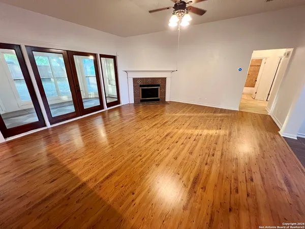 a view of an empty room with wooden floor and a fireplace