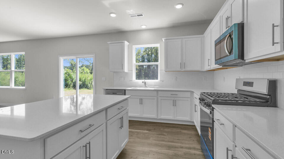 145 Westerly Way Lillington, NC 27546 - Photo 6 of 34 a kitchen with stainless steel appliances granite countertop a stove a sink and a microwave