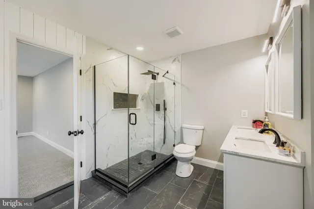 a bathroom with a granite countertop sink a toilet and shower