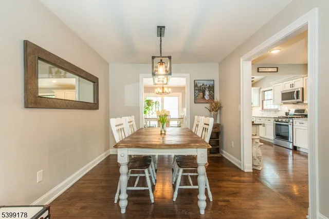 a dining room with wooden floor a chandelier a wooden table and chairs
