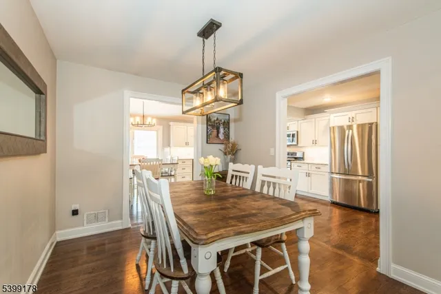 a dining room with wooden floor a chandelier a wooden table and chairs