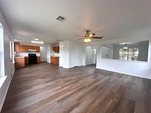 a view of an empty room with window and wooden floor