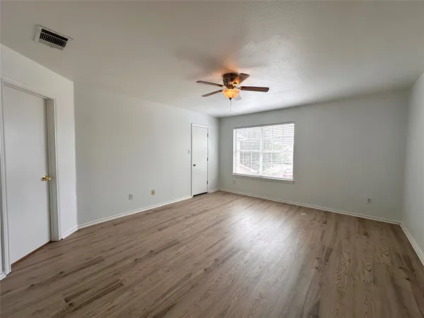 an empty room with wooden floor and windows