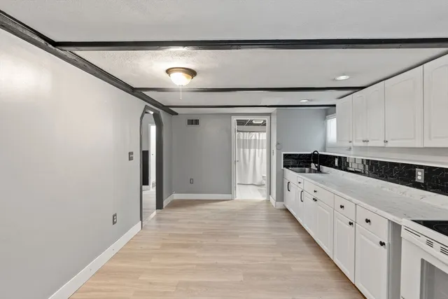 a large white kitchen with stainless steel appliances granite countertop a refrigerator and a stove top oven