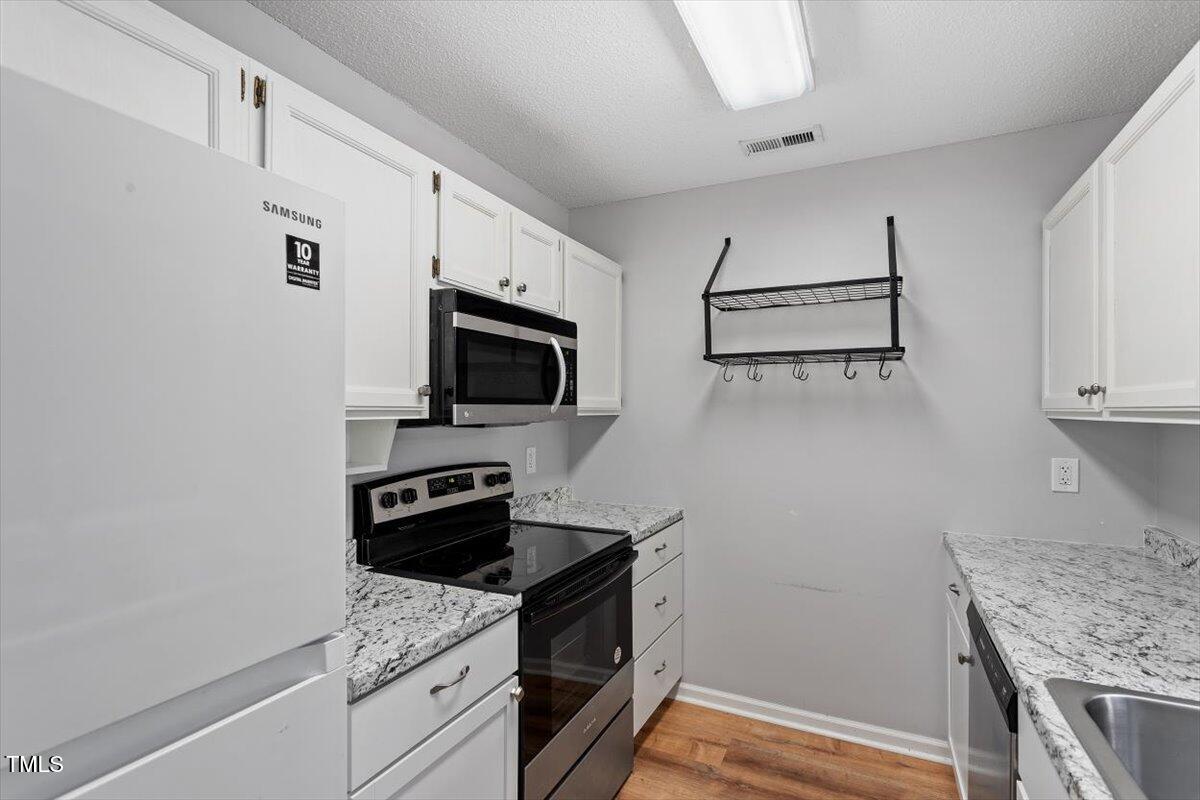 69 Forest Oaks Drive Durham, NC 27705 - Photo 11 of 31 a kitchen with white cabinets stainless steel appliances and a counter space