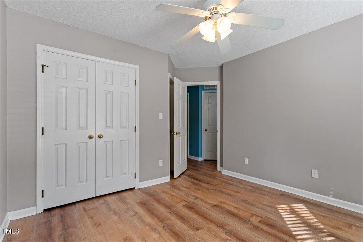 69 Forest Oaks Drive Durham, NC 27705 - Photo 22 of 31 a view of an empty room with wooden floor and a ceiling fan