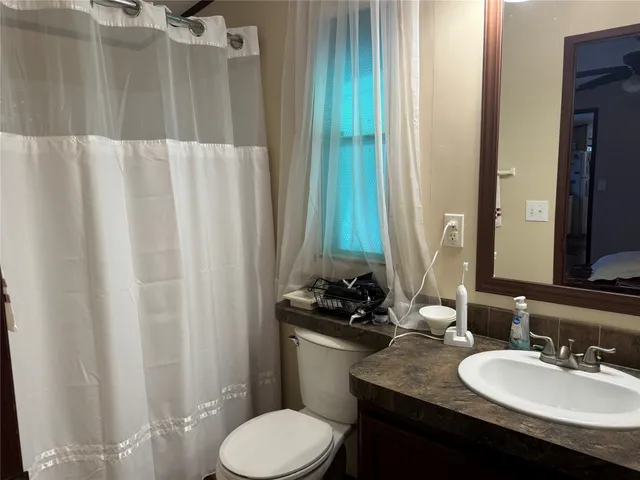 a bathroom with a granite countertop sink and a mirror with toilet