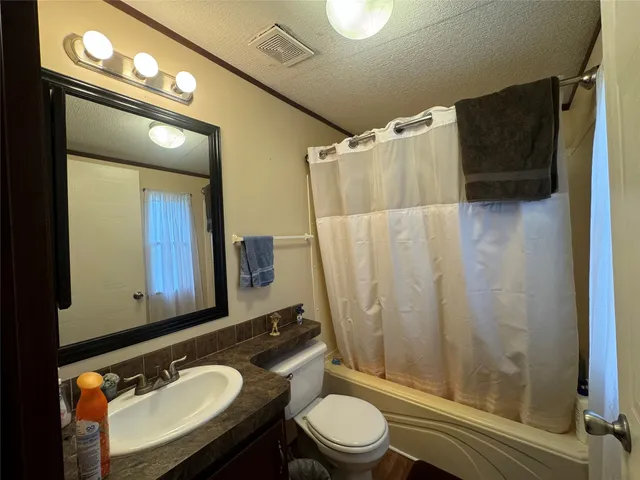 a bathroom with a granite countertop sink toilet a mirror a vanity and shower