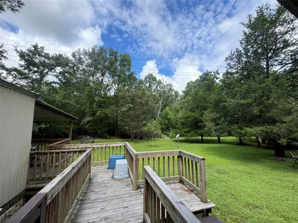 a balcony with wooden floor and trees in the background