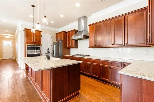 a kitchen with stainless steel appliances granite countertop a sink a stove and a wooden floors
