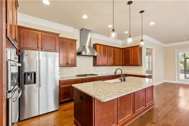 a kitchen with stainless steel appliances granite countertop a sink a refrigerator a center island and wooden floor