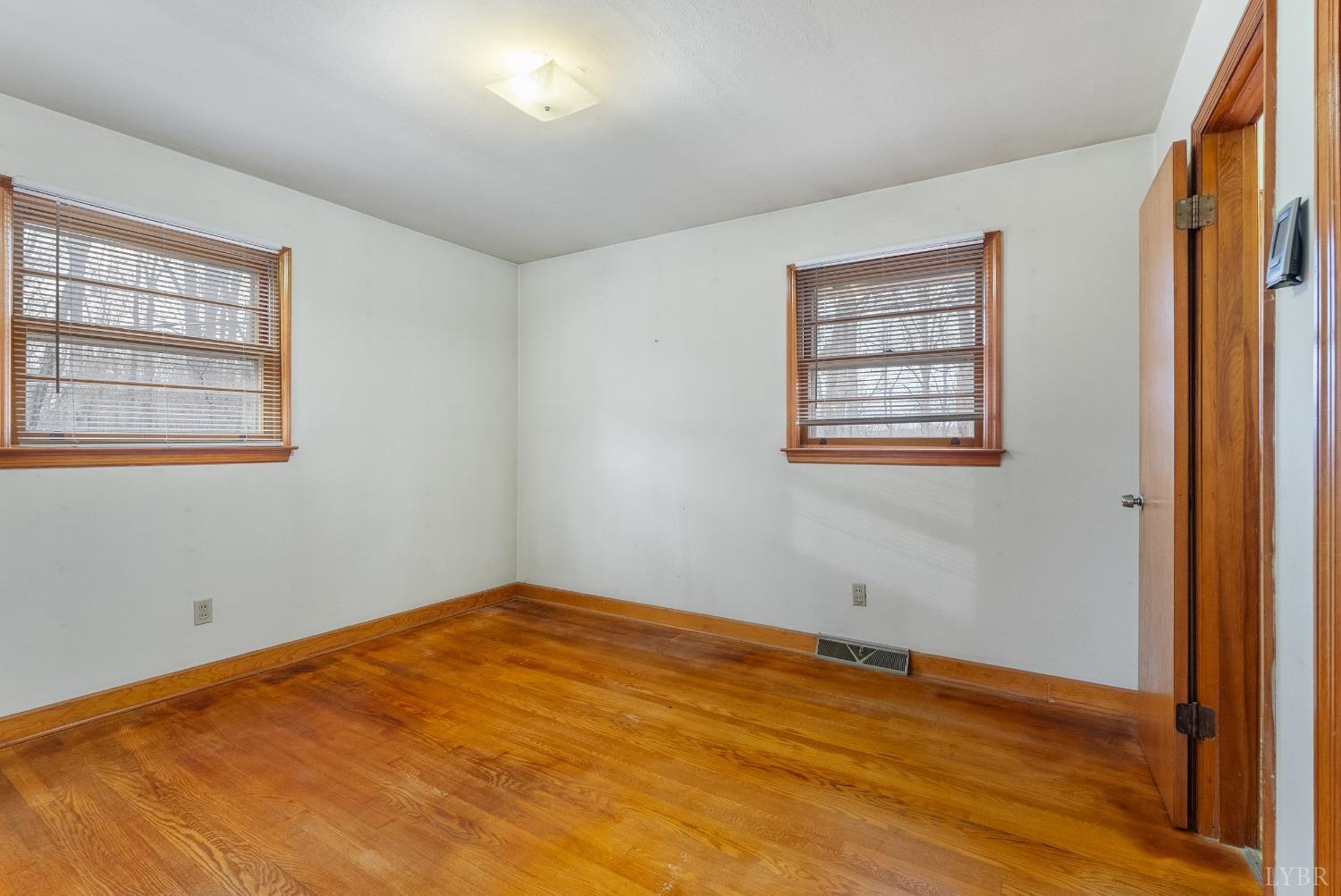 528 Jasper Wood Road Hurt, VA 24563 - Photo 26 of 44 an empty room with wooden floor and windows