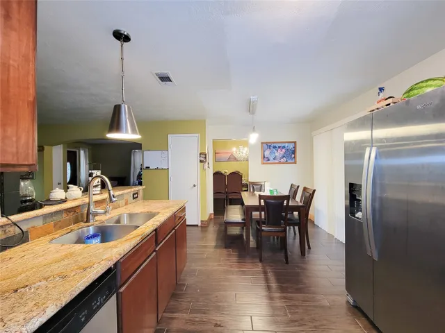a dining hall with stainless steel appliances granite countertop a sink dishwasher and a dining table with chairs