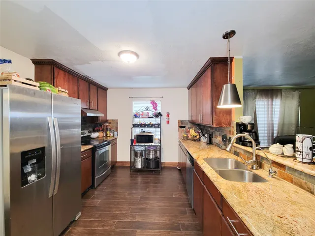 a kitchen with stainless steel appliances granite countertop a sink refrigerator and cabinets