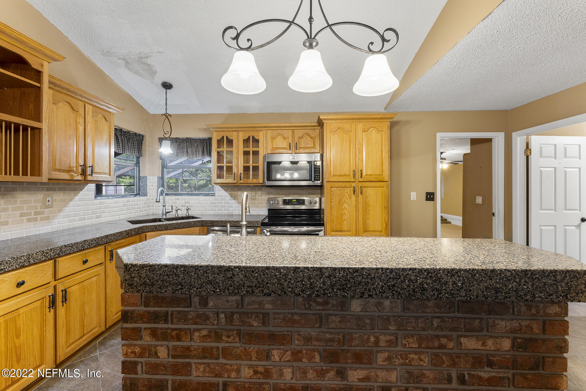 6130 Firestone Road Jacksonville, FL 32244 - Photo 13 of 67 a large kitchen with stainless steel appliances kitchen island granite countertop a sink and cabinets