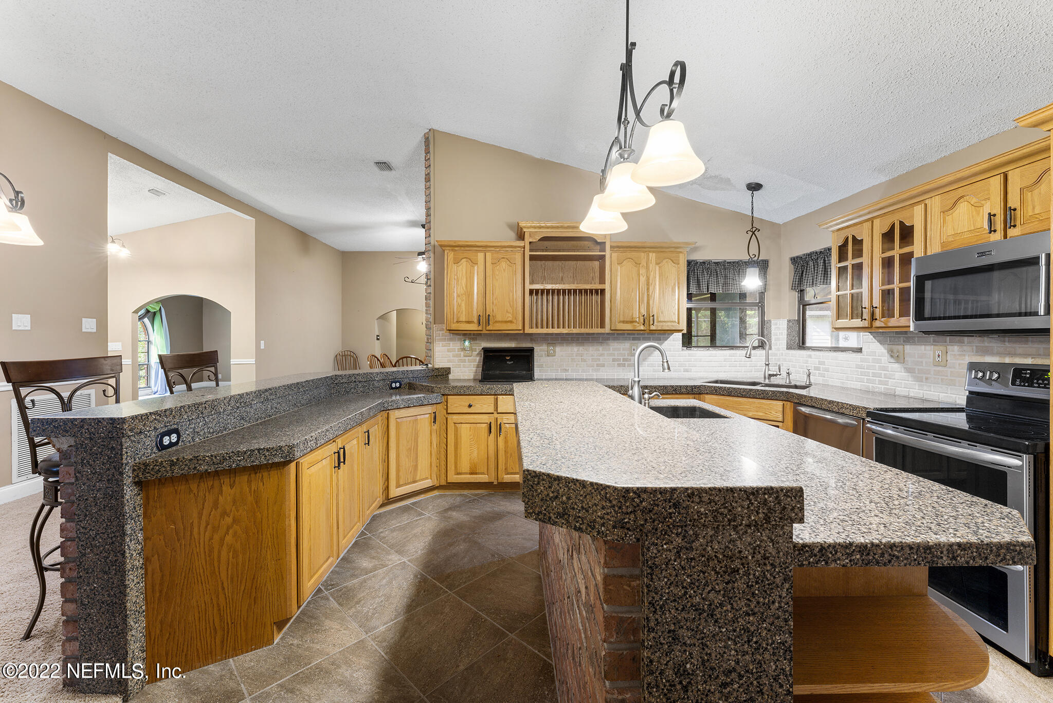 6130 Firestone Road Jacksonville, FL 32244 - Photo 36 of 67 a large kitchen with granite countertop a sink a counter top space appliances and cabinets