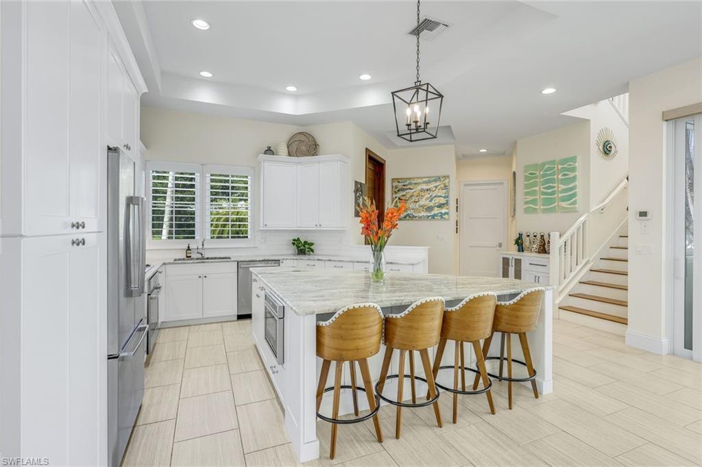 9161 Mercato Way Naples, FL 34108 - Photo 11 of 50 a kitchen with stainless steel appliances granite countertop a kitchen island a stove a table and chairs in it
