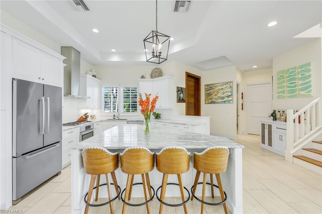 9161 Mercato Way Naples, FL 34108 - Photo 12 of 50 a dining room with stainless steel appliances kitchen island granite countertop a table chairs and a refrigerator