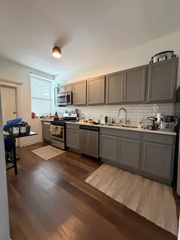 a kitchen with stainless steel appliances granite countertop a sink dishwasher stove top oven and cabinets with wooden floor