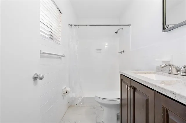 a bathroom with a granite countertop sink toilet and shower