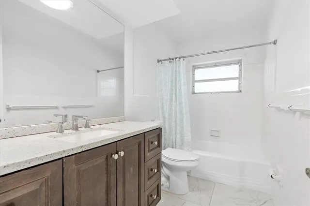 a bathroom with a granite countertop sink a toilet and shower