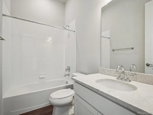 a bathroom with a granite countertop sink a toilet and shower