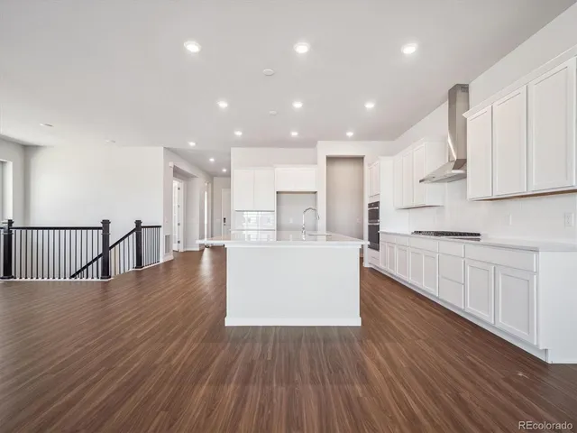 a large kitchen with stainless steel appliances refrigerator a stove top oven with wooden floors