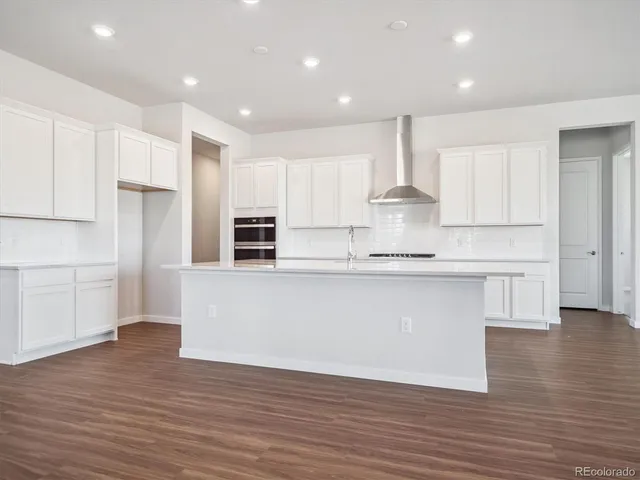 a large kitchen with stainless steel appliances granite countertop a stove a sink and white cabinets