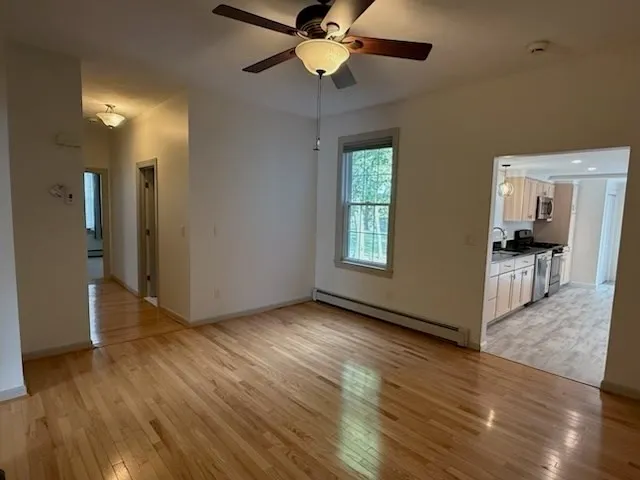 a view of an empty room with window and wooden floor