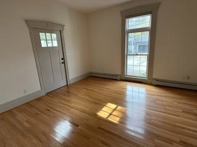 an empty room with wooden floor and windows