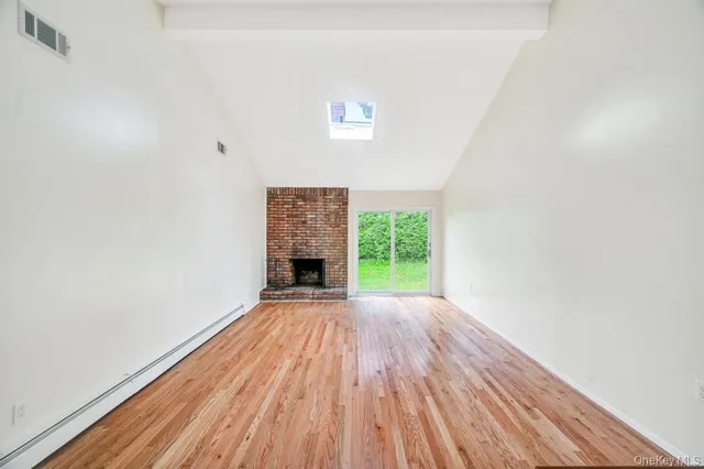 a view of empty room with wooden floor and fireplace