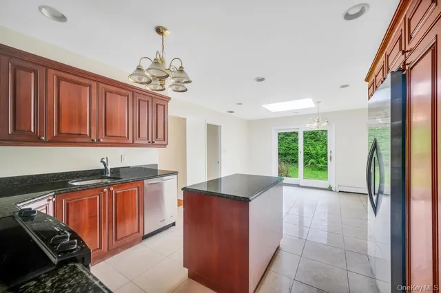 a kitchen with granite countertop stainless steel appliances a sink stove and cabinets