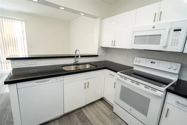 a kitchen with granite countertop white cabinets and white appliances