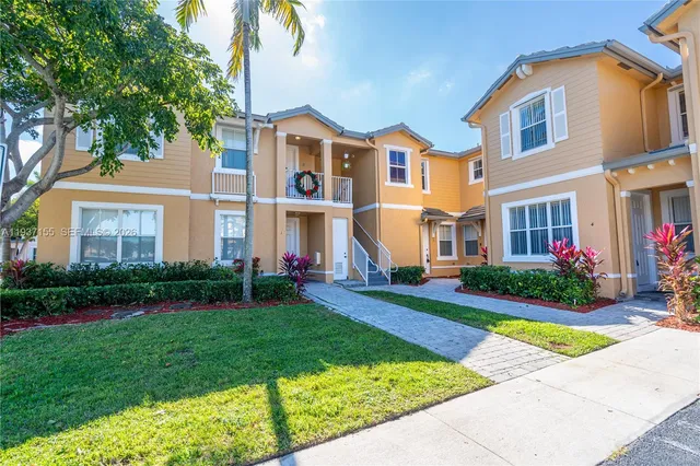 a view of a brick house with a yard and plants