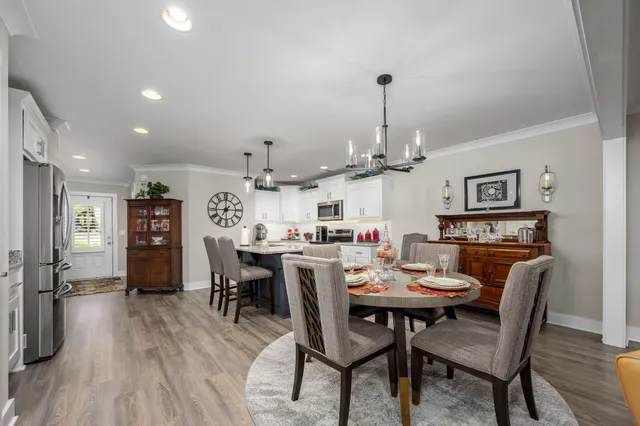 a view of a dining room and livingroom with furniture wooden floor a chandelier