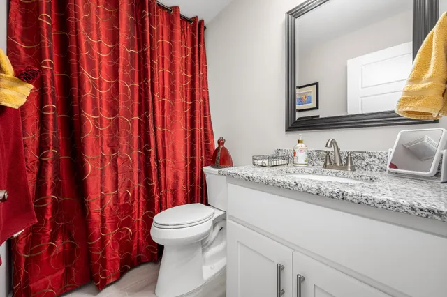 a bathroom with a granite countertop sink and a toilet